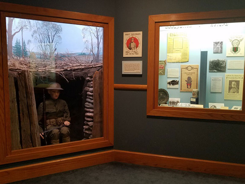 Two US Army museum displays behind glass windows.